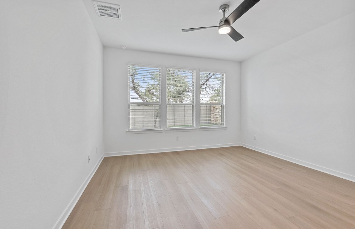 1700 Spg Mountain Cove Georgetown, TX 78628 - Photo 14 of 40 an empty room with wooden floor chandelier fan and windows