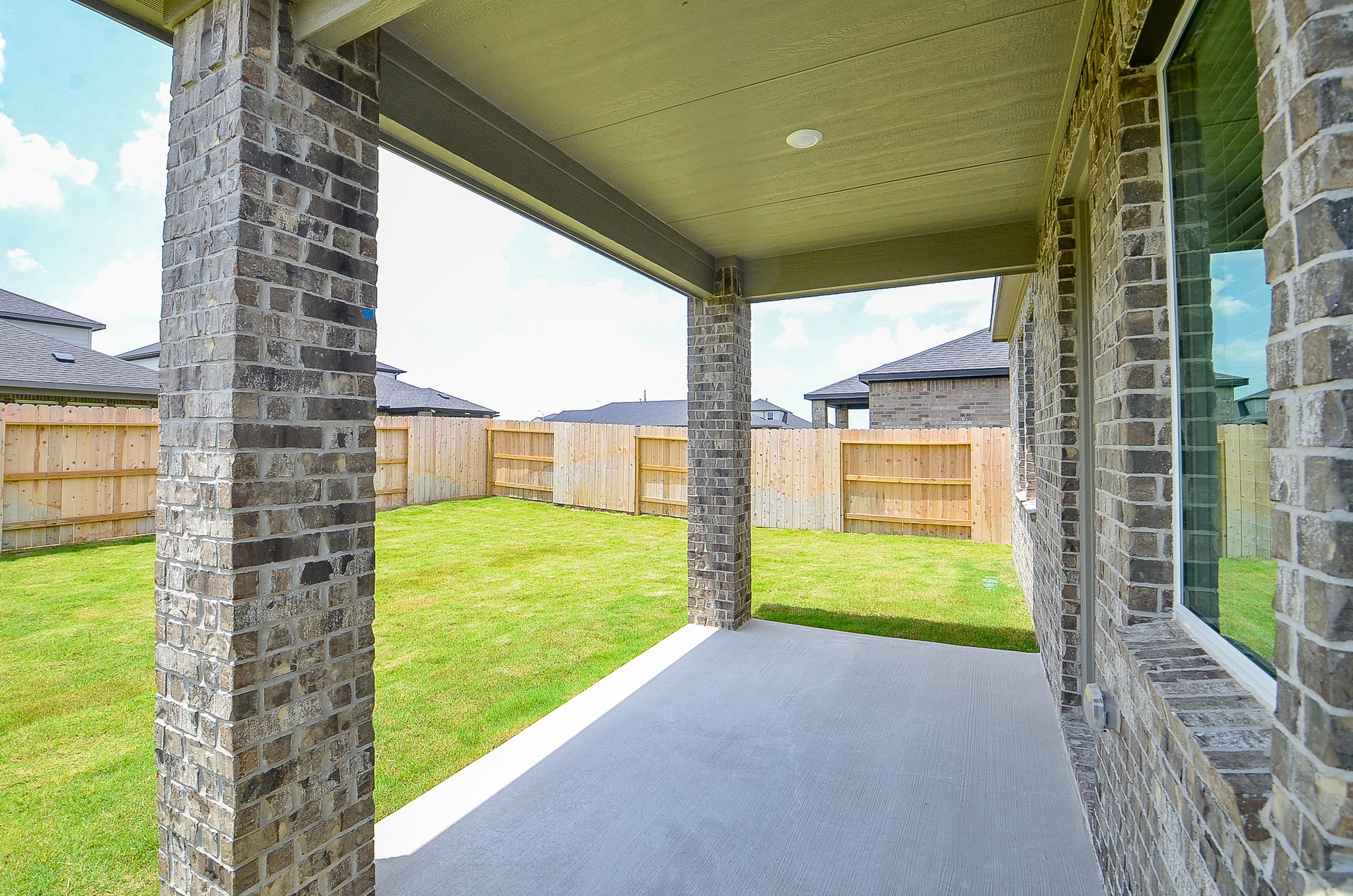 9727 Rialto Hts Drive Cypress, TX 77433 - Photo 36 of 37 This photo shows the backyard of a single-story brick home with a covered patio area. The yard is spacious and enclosed by a wooden fence, offering privacy.