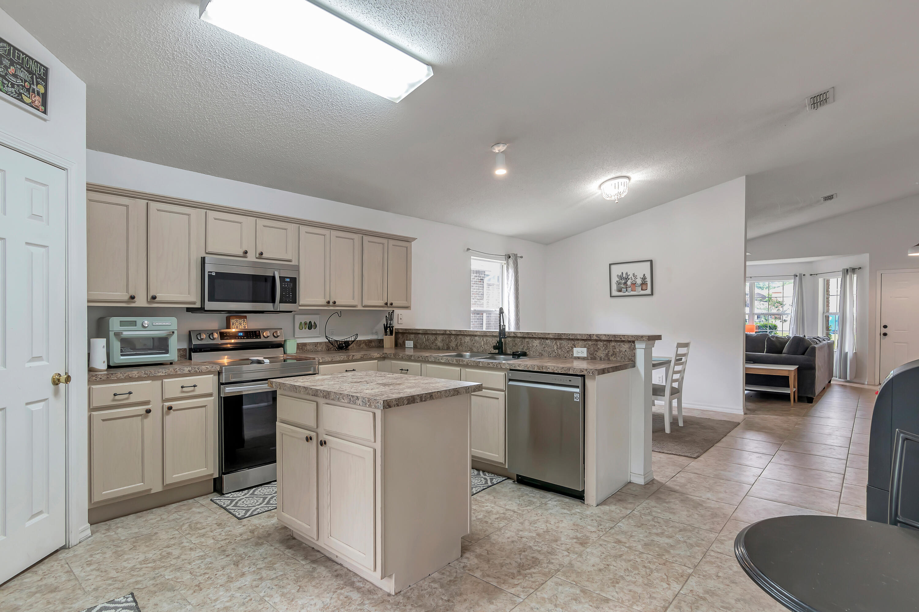 270 Limestone Circle Crestview, FL 32539 - Photo 12 of 35 a kitchen with stainless steel appliances granite countertop a stove top oven a sink dishwasher a dining table and chairs with wooden floor
