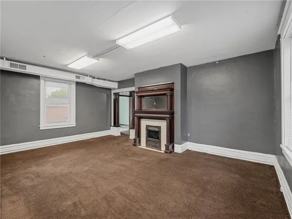 an empty room with windows and fireplace