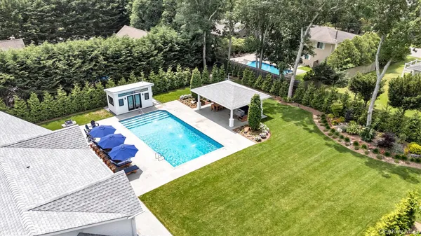 an aerial view of a house with swimming pool and trees
