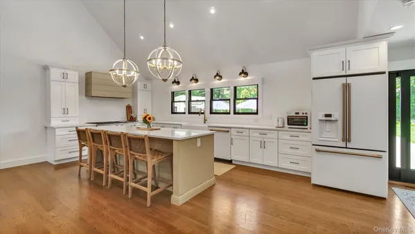 a kitchen with stainless steel appliances a dining table chairs stove refrigerator and cabinets