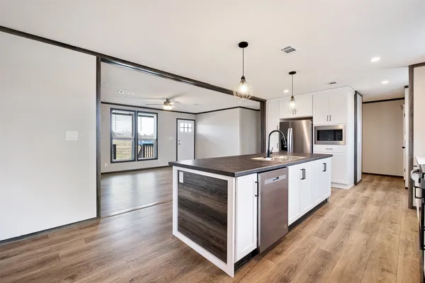 a kitchen with stainless steel appliances kitchen island a large counter tops a stove a sink and a refrigerator