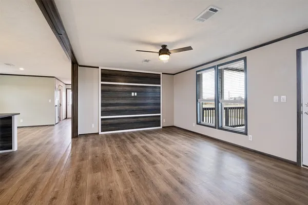 a view of an empty room with a window and wooden floor