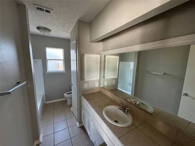 a bathroom with a granite countertop sink a mirror and a toilet