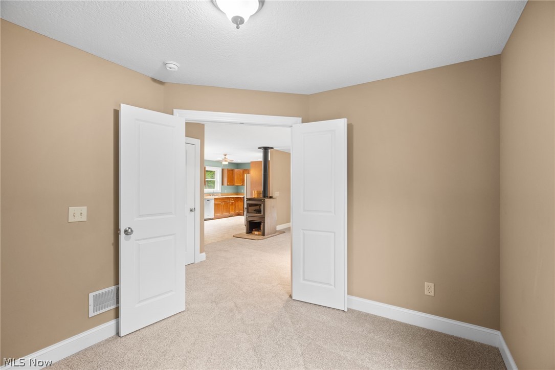 16985 Moseley Road Thompson, OH 44086 - Photo 9 of 22 Unfurnished room with light carpet and a wood stove