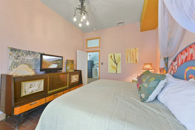 a bedroom with a bed a mirror on dresser and a chandelier