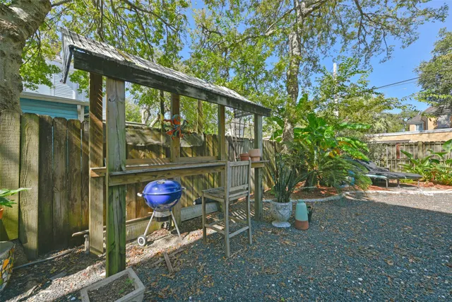 a view of a patio with couches table and chairs under an umbrella with a barbeque