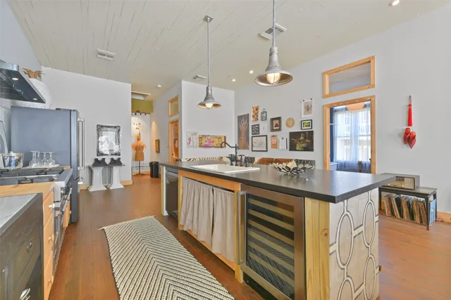 a kitchen with stainless steel appliances granite countertop a stove a sink dishwasher and a dining table with wooden floor