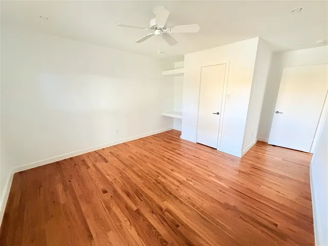 an empty room with wooden floor and fan