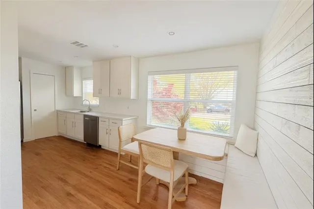 a kitchen with a table chairs a sink dishwasher window and cabinets