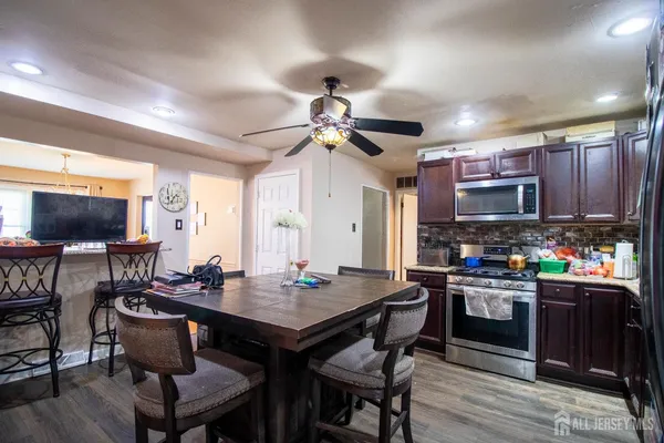 a kitchen with stainless steel appliances granite countertop a stove a refrigerator a kitchen island a table and chairs
