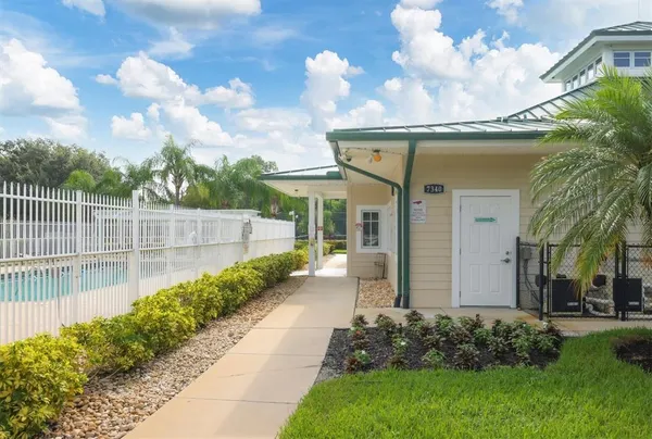 a view of a white house next to a yard with big trees
