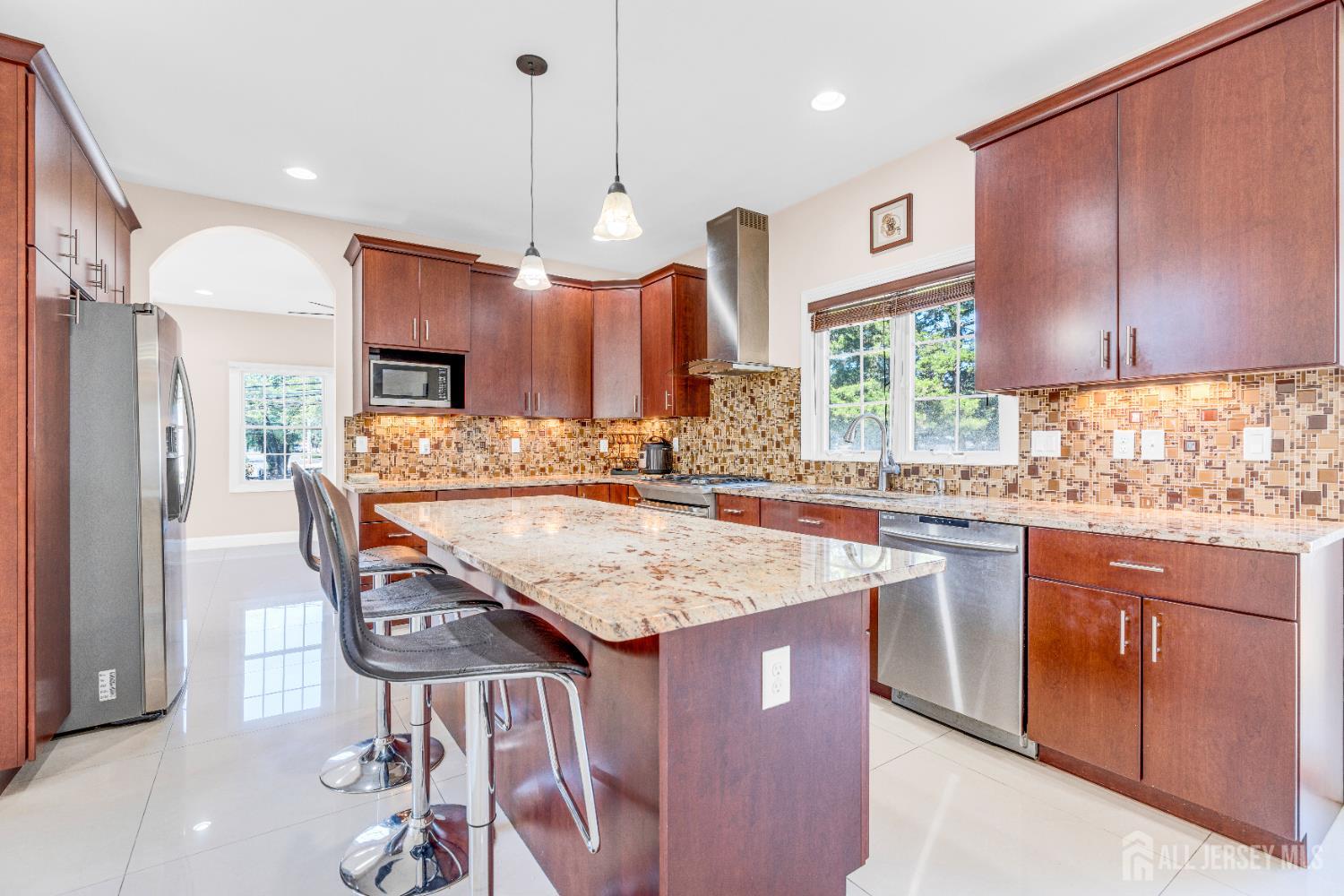 114 Holly Road Iselin, NJ 08830 - Photo 13 of 47 a kitchen with stainless steel appliances kitchen island granite countertop a table chairs in it and wooden floors