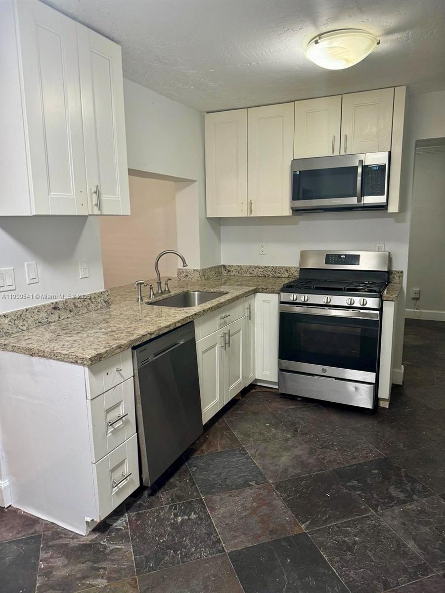 8670 Northwest 28th Place Sunrise, FL 33322 - Photo 4 of 13 a kitchen with stainless steel appliances granite countertop a sink stove and microwave