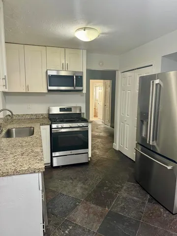 a kitchen with stainless steel appliances granite countertop a stove a refrigerator and a sink