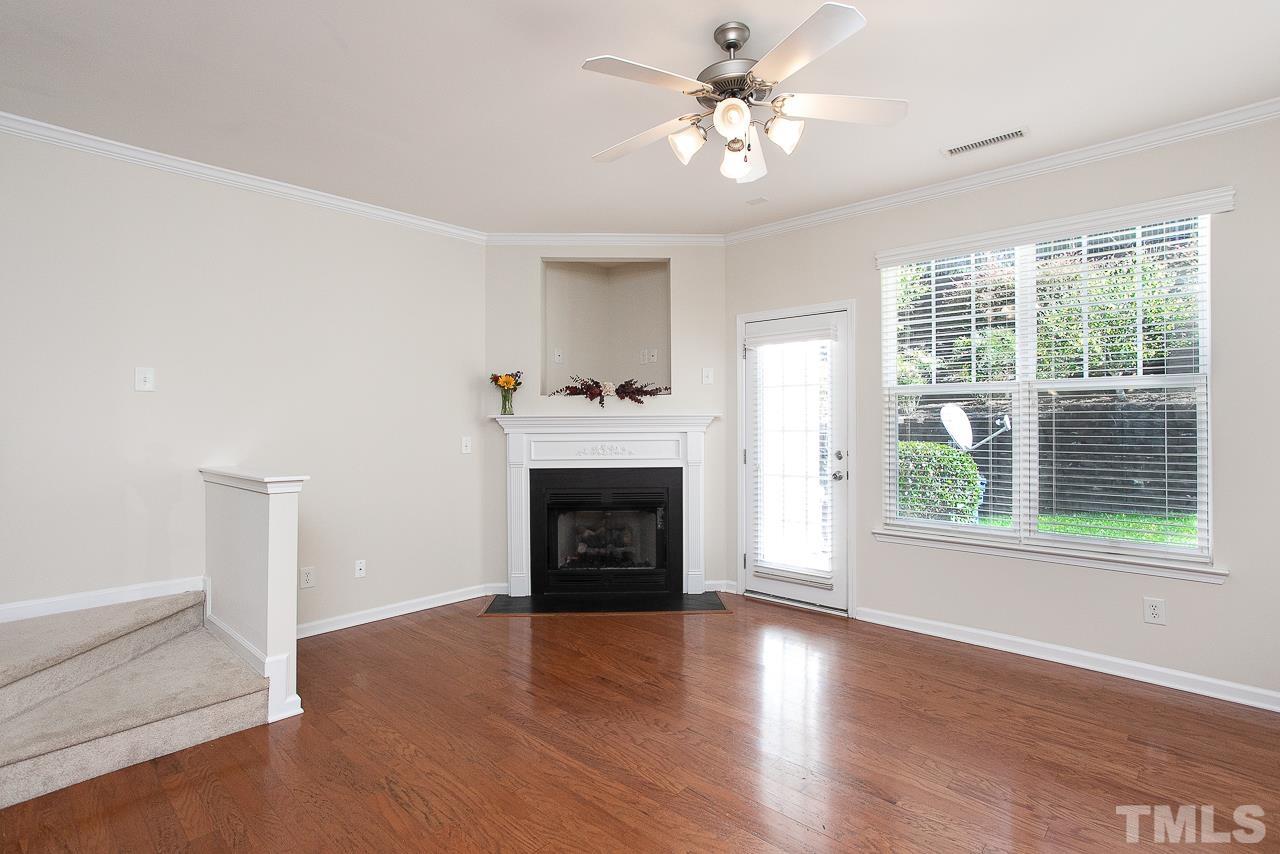 6016 Viking Drive Raleigh, NC 27612 - Photo 9 of 18 an empty room with windows fireplace and wooden floor