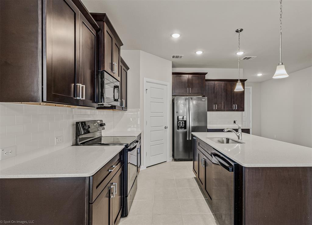 638 Pinehurst Road Red Oak, TX 75154 - Photo 33 of 38 Kitchen with dark wood finish cabinets, black appliances, decorative backsplash, pendant lighting, and a kitchen island with sink