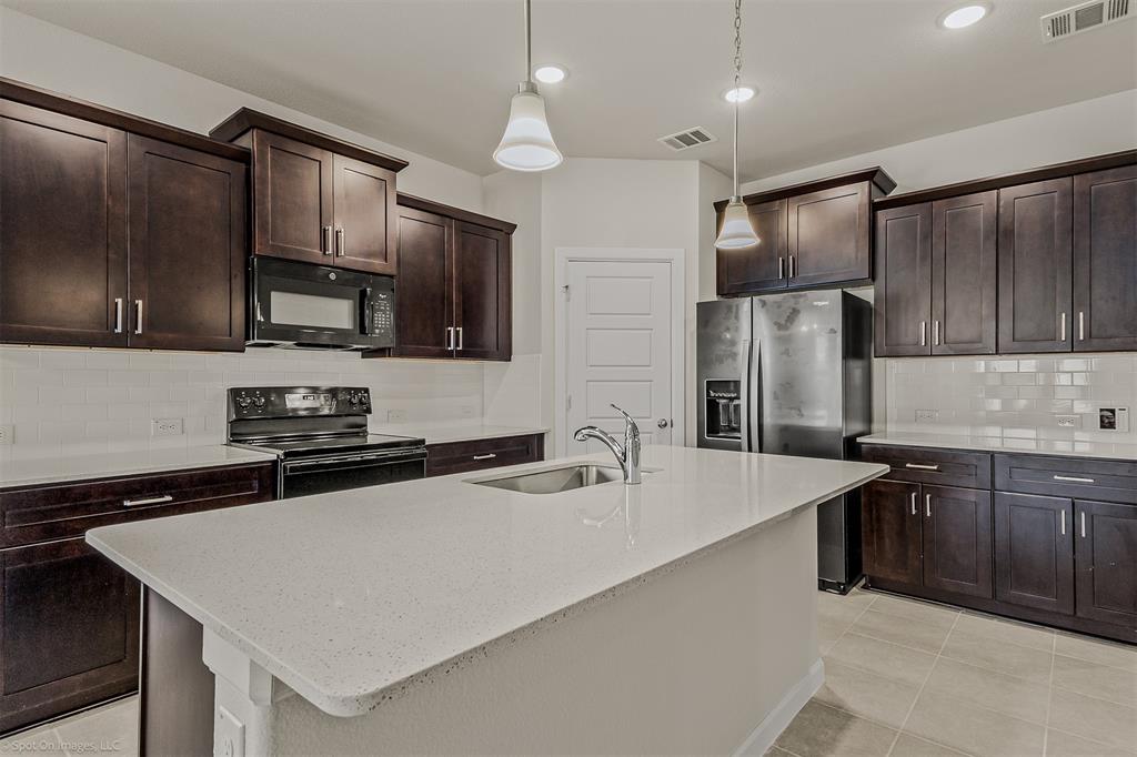 638 Pinehurst Road Red Oak, TX 75154 - Photo 34 of 38 Kitchen featuring backsplash, light stone counters, black appliances, and dark wood finish cabinets