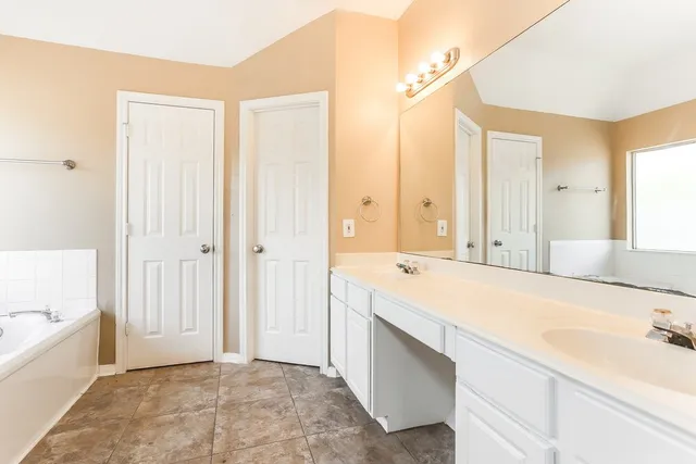 a spacious bathroom with a tub sink and mirror