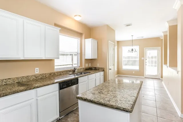 a kitchen with stainless steel appliances granite countertop a stove a sink and a white cabinets
