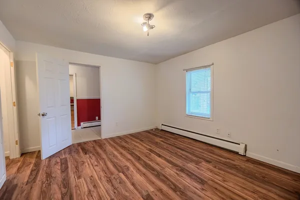 an empty room with wooden floor and fan