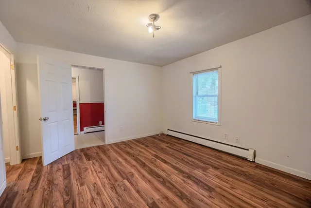 an empty room with wooden floor and fan