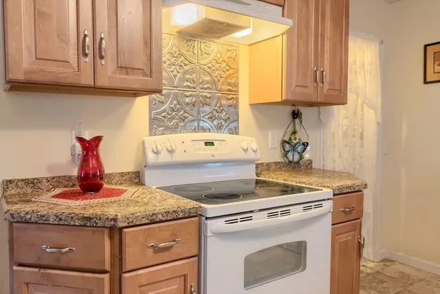 a kitchen with granite countertop white cabinets and a stove