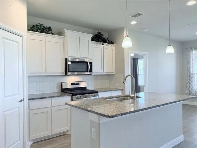 a kitchen with stainless steel appliances granite countertop a sink a stove and a refrigerator