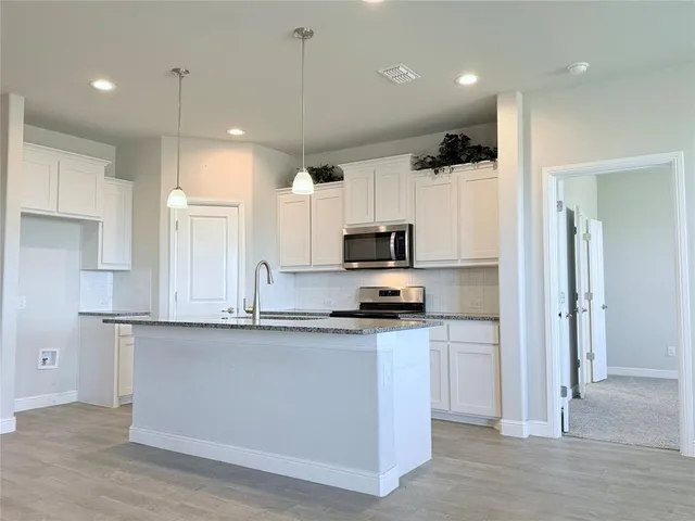 a kitchen with stainless steel appliances a sink a stove a refrigerator and cabinets