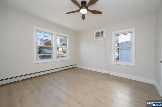 a view of an empty room with window and a ceiling fan