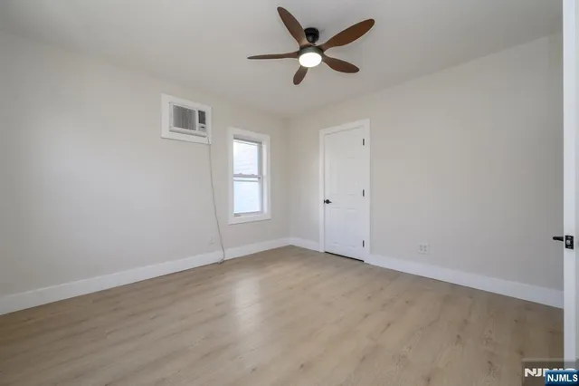 an empty room with wooden floor ceiling fan and windows