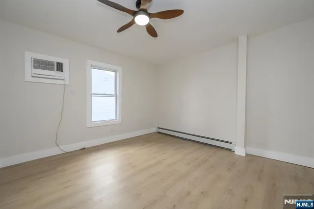 an empty room with wooden floor fan and windows