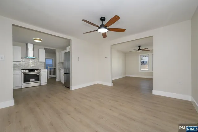 a view of an empty room with a fireplace and a ceiling fan