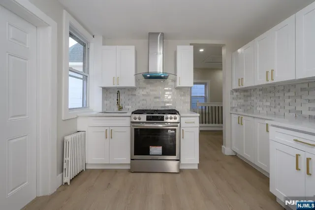 a kitchen with stainless steel appliances granite countertop a stove a sink and white cabinets