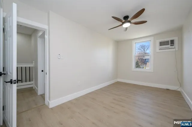 an empty room with wooden floor a ceiling fan and windows