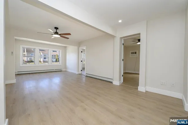a view of an empty room with a window and wooden floor