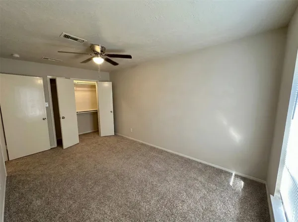 an empty room with a windows and a ceiling fan