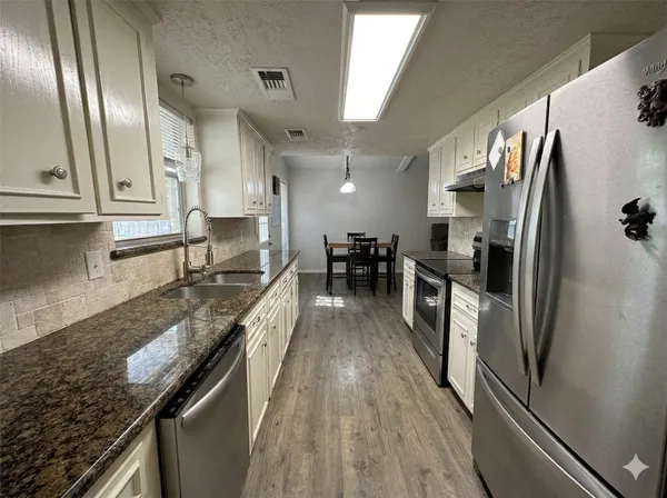 a kitchen with stainless steel appliances granite countertop a refrigerator a stove and a sink