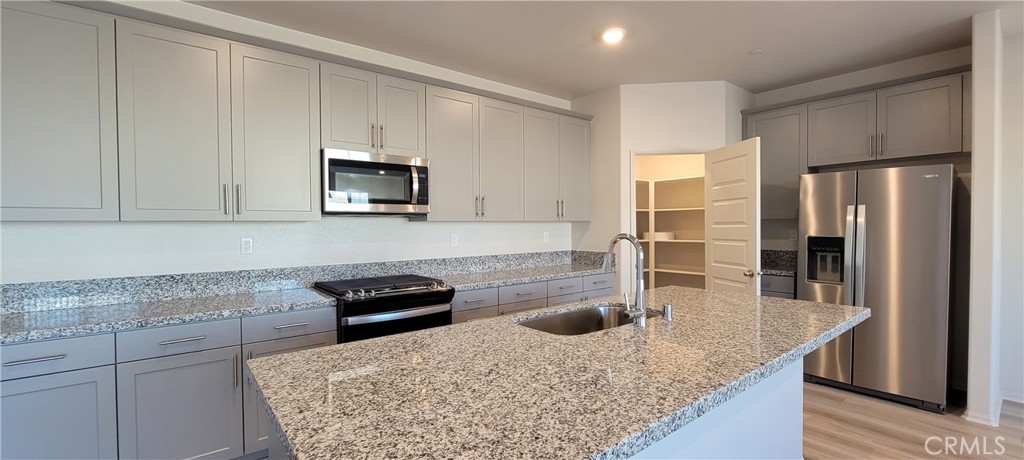 32916 Earlsburn Circle Menifee, CA 92584 - Photo 13 of 34 a kitchen with granite countertop a sink a stove and refrigerator