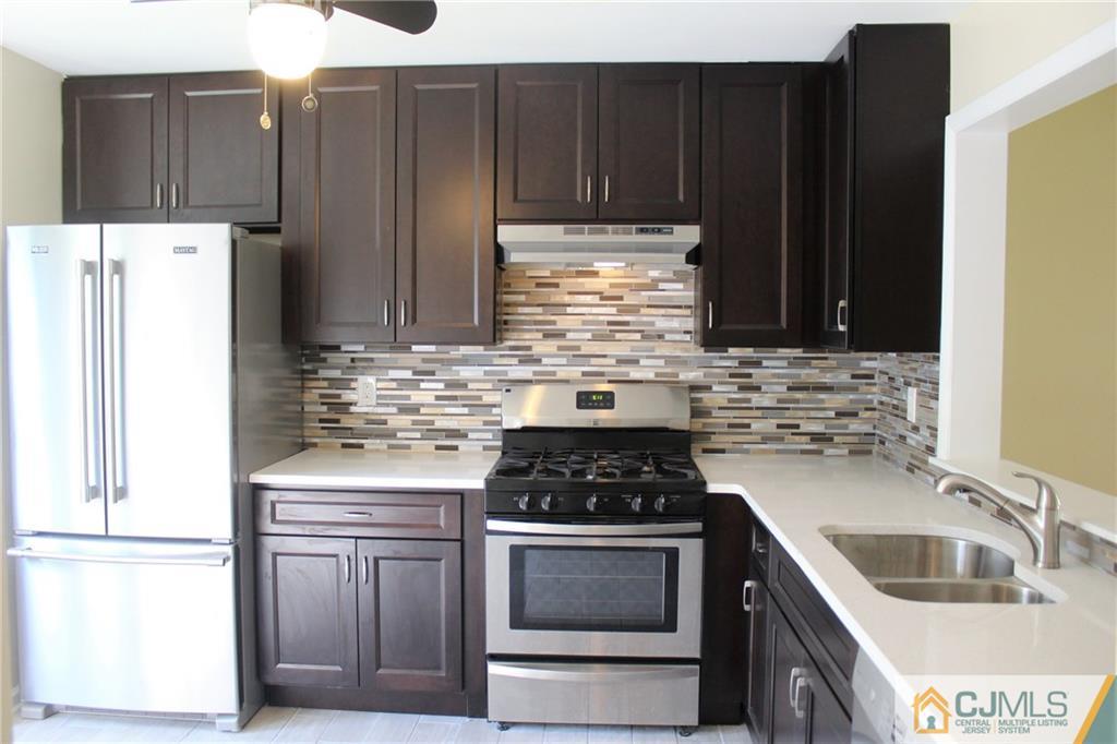 903 Timber Oaks Road, Unit 903 Edison, NJ 08820 - Photo 3 of 34 a kitchen with stainless steel appliances a stove a sink and a refrigerator with wooden cabinets