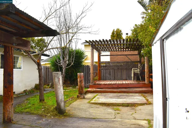 a view of a house with a large tree and a yard with wooden fence