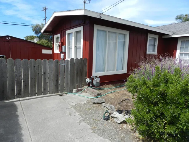 a backyard of a house with table and chairs under an umbrella