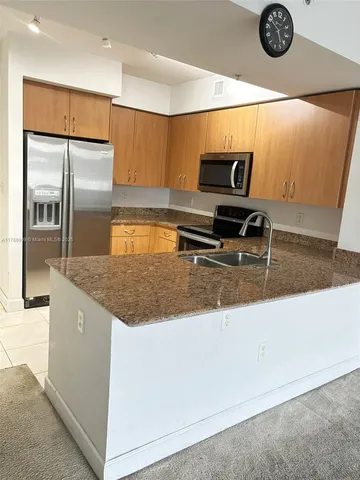 a kitchen with kitchen island granite countertop a sink and a refrigerator