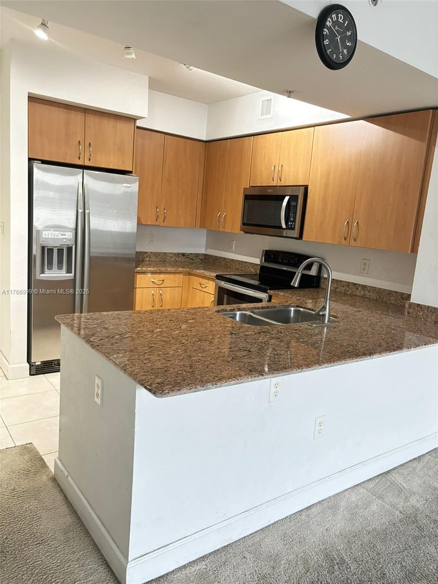 1830 Radius Drive, Unit 604 Hollywood, FL 33020 - Photo 7 of 22 a kitchen with kitchen island granite countertop a sink and a refrigerator