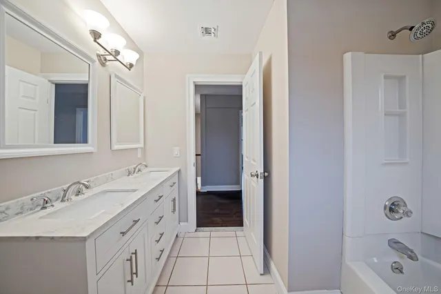 a bathroom with a double vanity sink a mirror and a bathtub