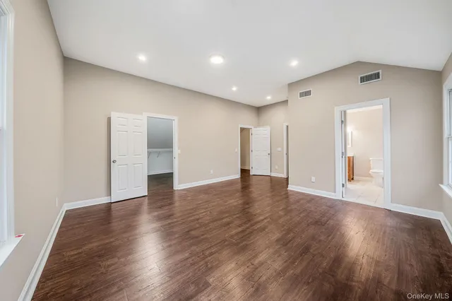 a view of an empty room with wooden floor and closet