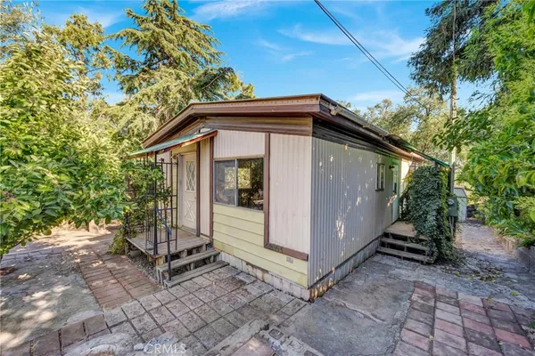 a view of a small house with a small yard and a large tree