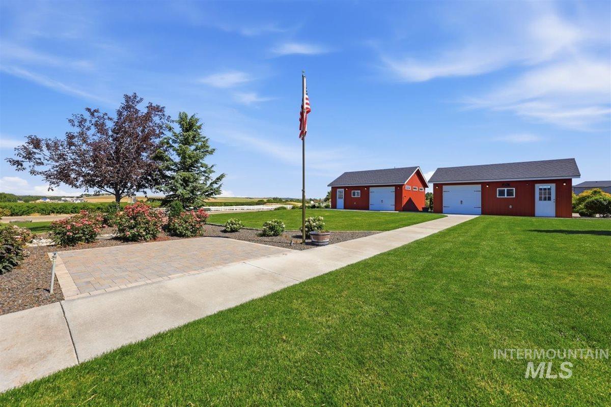 13496 Hockberger Ranch Road Caldwell, ID 83607 - Photo 30 of 40 Two red outbuildings with white garage doors and exterior doors, surrounded by a green lawn