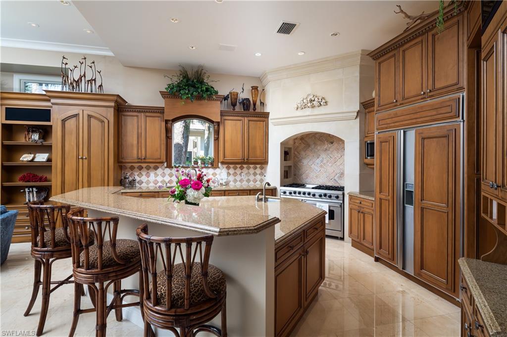 980 Barcarmil Way Naples, FL 34110 - Photo 13 of 50 a kitchen with stainless steel appliances granite countertop a dining table and chairs